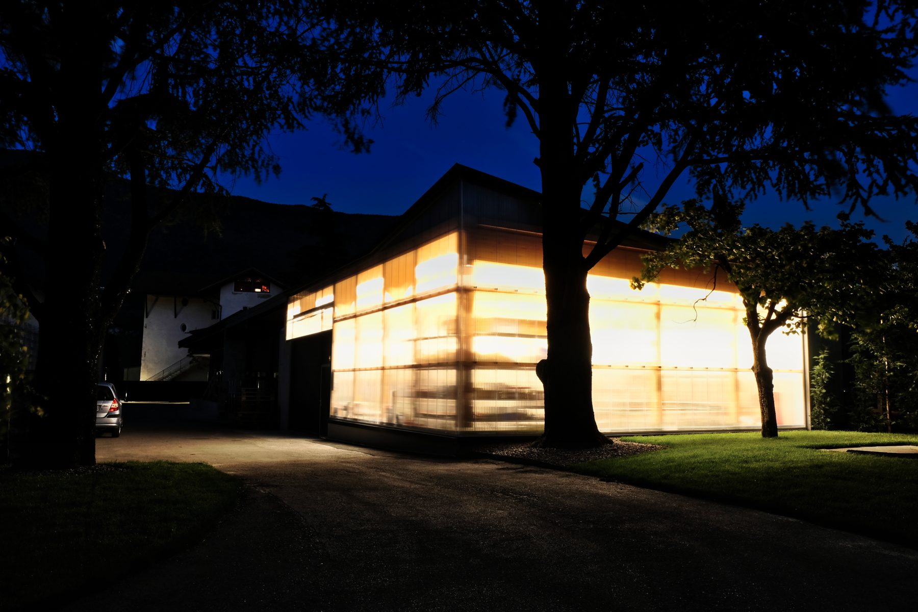 Facciata traslucida illuminata di sera dell'impianto di imbottigliamento Castelfeder
